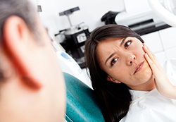 woman in dentist chair holding jaw in tooth pain dental emergency, needs emergency dentist Kitchener, ON